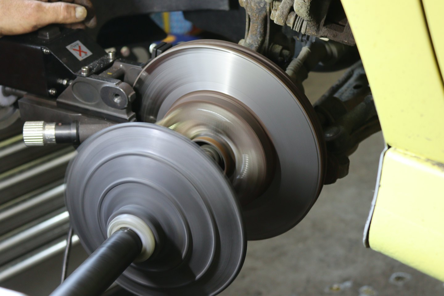 Mechanic resurfacing a car brake rotor with a brake lathe.