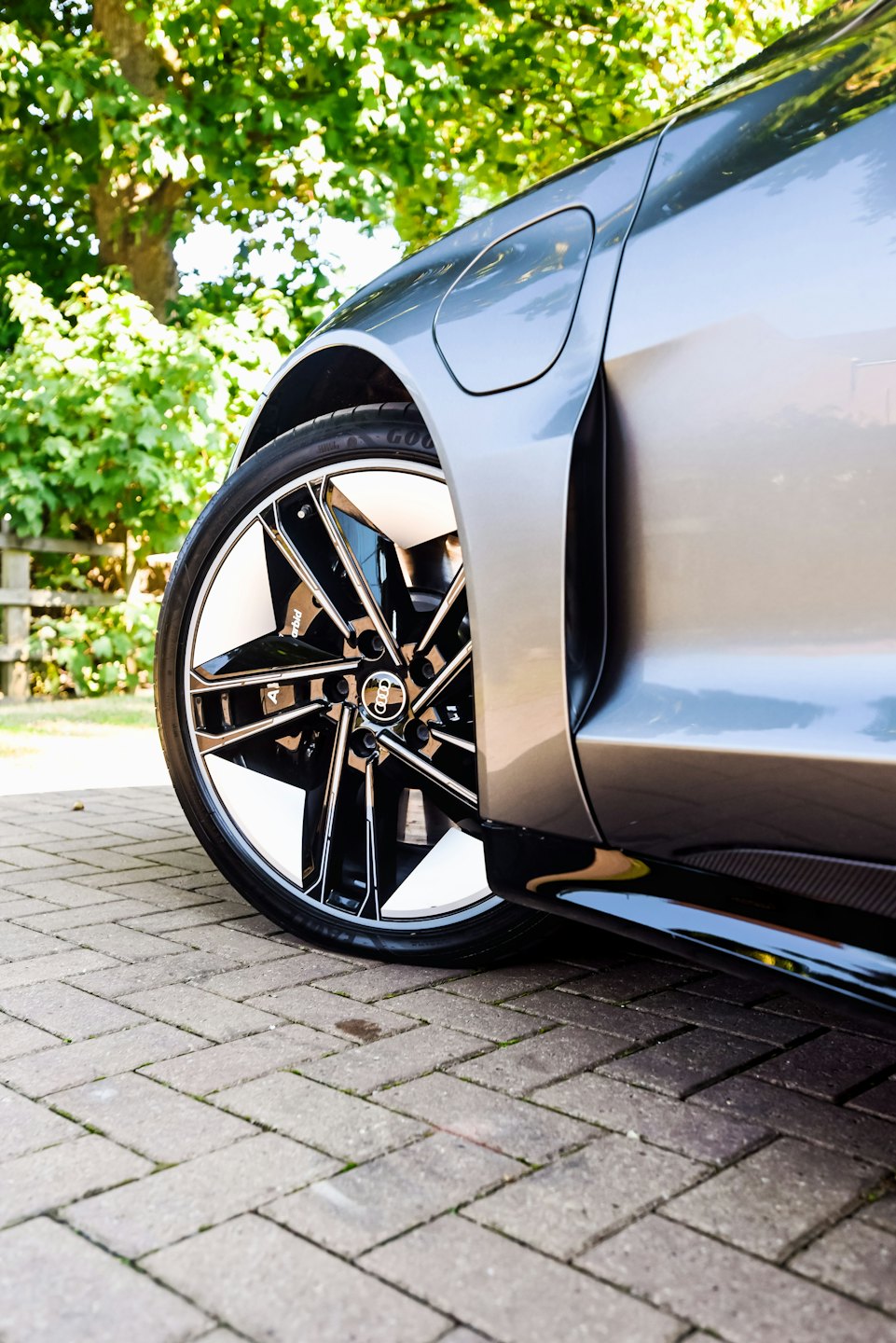 Grey car wheel on a brick paver driveway.